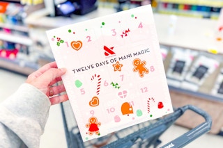 person holding a olive & june mani. magic advent calendar over a cart