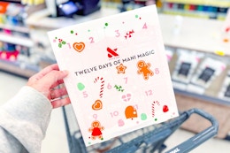 person holding a olive & june mani. magic advent calendar over a cart