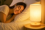 a woman sleeping next to a table lamp