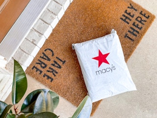 A Macy's online order package on a mat outside a front door.