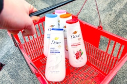 hand holding a red shopping basket with dove body washes