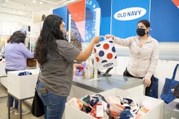 An Old Navy employee handing a customer her bag over the checkout counter at Old Navy.
