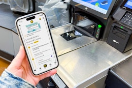 hand holding smartphone next to cash register with a kcl app 1-clip deal on the phone