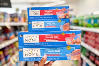 Hand holding a stack of four boxes of Complete Home storage bag boxes