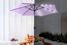 Lifestyle image of a lavender patio umbrella with LED lights shown in daytime and nighttime 