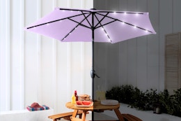 Lifestyle image of a lavender patio umbrella with LED lights shown in daytime and nighttime 