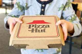 a boy holding a pizza hut personal pan pizza