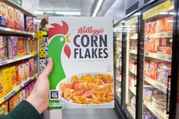hand holding up a box of kellogg's corn flakes cereal