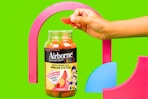 Stock image of the Airborne Kids Immune Support Gummies — one being taken out of bottle with shapes in the background
