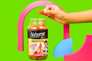 Stock image of the Airborne Kids Immune Support Gummies — one being taken out of bottle with shapes in the background