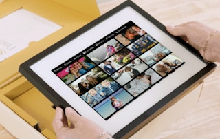 hands holding a digital picture frame over a box