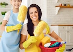 two people with cleaning aprons holding yellow dusters and cleaning products