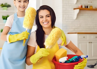 two people with cleaning aprons holding yellow dusters and cleaning products