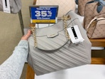 A person holding a designer handbag next to a sign, "todays deal 35% off"