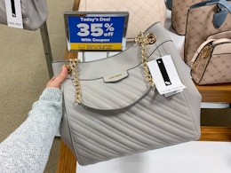 A person holding a designer handbag next to a sign, "todays deal 35% off"