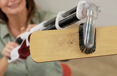 a person using a handheld vacuum to clean a ceiling fan 