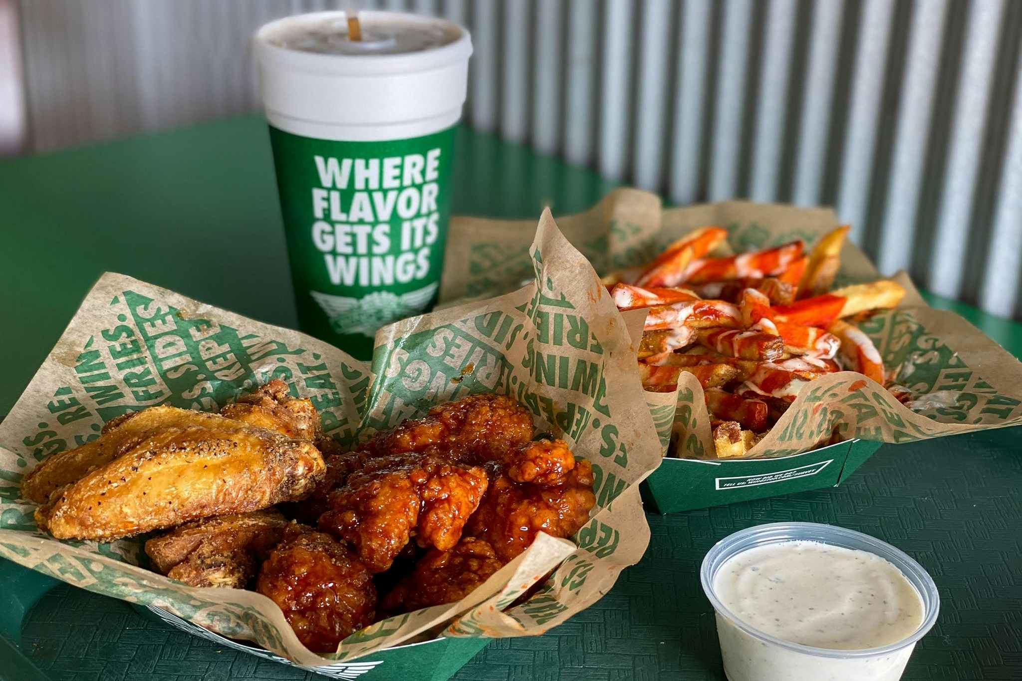 Wingstop wings, fries, and a drink sitting together on a table at Wingstop.