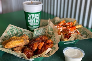 Wingstop wings, fries, and a drink sitting together on a table at Wingstop.