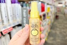person holding sun bum leave-in conditioner in front of the hair care aisle