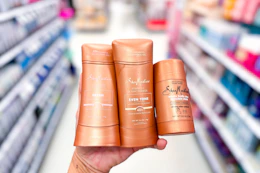 person holding 3 shea moisture deodorants in an aisle