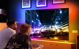 two people playing a video game on a TV with LED lights behind it