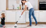a woman cleaning her home with an electric spin scrubber