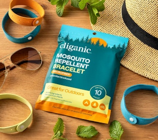 loose bracelets on a wooden table next to its packaging, a hat, and sunglasses