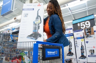 a woman placing a vacuum in a walmart  shopping cart 