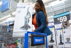 a woman placing a vacuum in a walmart shopping cart