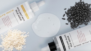 two bottles of facial serum next to piles of rice