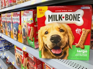A box of Milk Bone dog treats on a shelf with more dog treats in the pet section at Walmart.