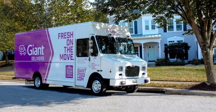 Giant food white and purple delivery truck parked in front of a house.