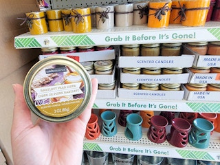 hand holding a bartlett pear cider scented candle in front of other candles