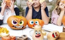 sticker faces on pumpkins at a table with kids