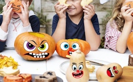 sticker faces on pumpkins at a table with kids