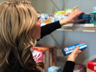 A woman pulling toothpaste from her stockpile in her home.