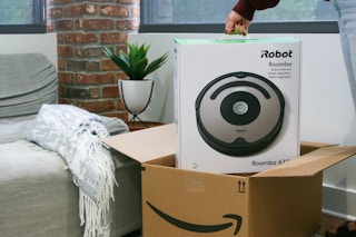 Someone taking an iRobot Roomba out of an Amazon box