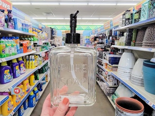 hand holding a glass soap dispenser
