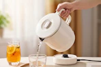 Lifestyle image of an electric kettle being used to pour water