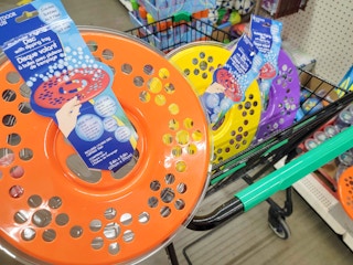 hand holding a bubble flying disc in front of a cart with two bubble flying discs in it