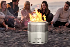 Lifestyle image of a group of friends at the beach roasting marshmallows around the fire