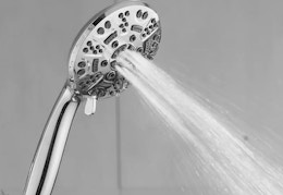 a silver shower head spraying water