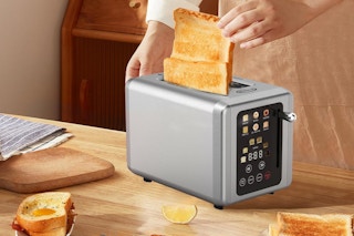 a person putting bread in a toaster on a wooden table with food