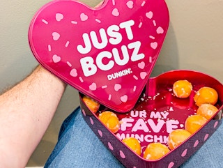 z person holding the heart shaped Dunkin donuts box on lap 