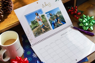 a photo calendar sitting on a desk next to some gift bows and a cup of coffee 