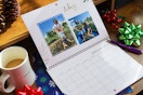 a photo calendar sitting on a desk next to some gift bows and a cup of coffee