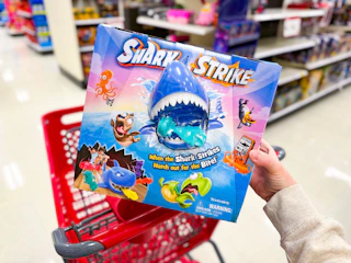 hand holding a shark strike game over a target cart