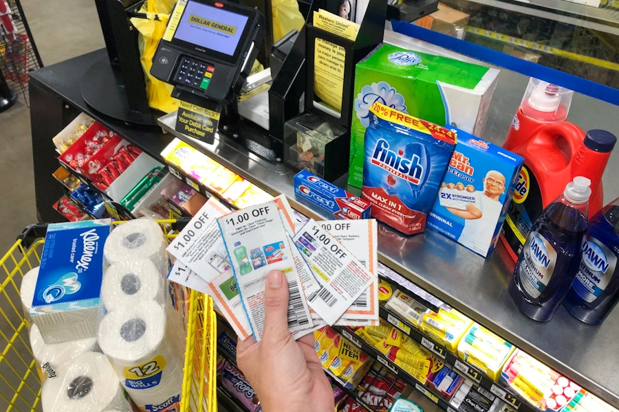 A person holding a stack of coupons next to products inside Dollar General