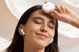 a woman holding wireless earbuds