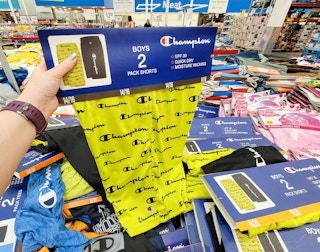 hand holding a 2 pack of kids champion shorts, one yellow one black